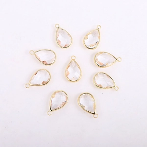 Macro view of faceted teardrop glass crystal charms with gold-plated metal borders