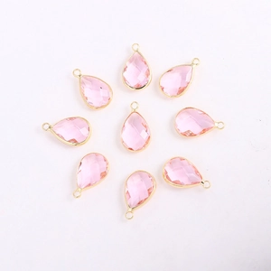 Close-up of pink faceted teardrop glass pendants with gold-plated metal edges and bails