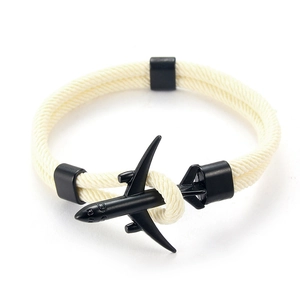Détail du charm avion et du cordon tressé crème sur ce bracelet pilote minimaliste
