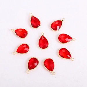 Detailed view of nine faceted red teardrop glass pendants with golden metal alloy frames