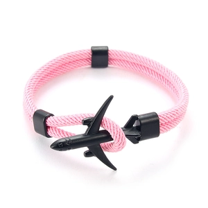 Gros plan d'un bracelet en paracorde rose avec un charme d'avion noir mat et boucle