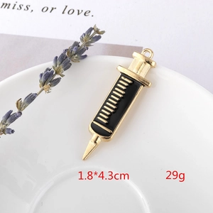 Macro shot of 1.8x4.3cm golden syringe charm with black enamel and measurement markings