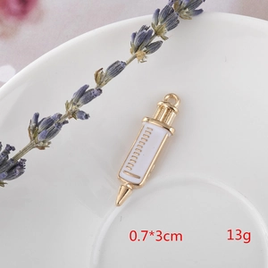 Detail of a 0.7x3cm gold syringe pendant with white enamel finish for DIY jewelry
