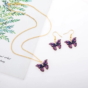 Detailed macro of pink and purple butterfly jewelry set with golden necklace chain