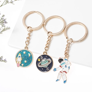 Detail van ruimte-sleutelhangers met blauwe emaille raket-, planeet- en astronaut-hangers