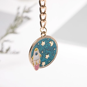 Detailopname van gouden astronaut raket sleutelhanger met blauwe glitter emaille