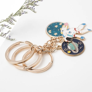 Ruimte-thema astronaut sleutelhanger met gouden ringen en blauwe hemelse bedeltjes op wit
