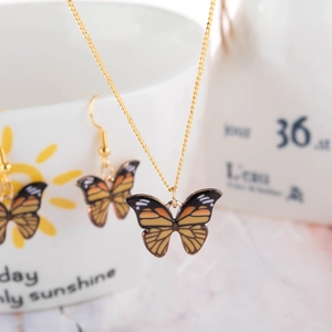 Fashion butterfly jewelry set with orange enamel necklace and matching earrings on cup