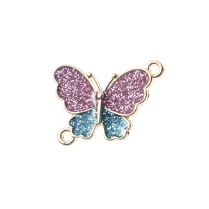 Macro shot of glitter butterfly pendant with gold base and purple blue enamel wings