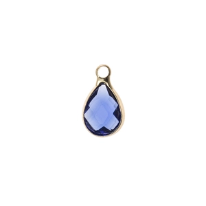 Détail macro d'un pendentif en cristal bleu foncé facetté en forme de poire avec bordure dorée