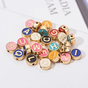 Macro-opname van kleurrijke emaille letterkralen met goudfinish voor DIY-sieraden