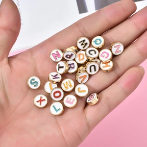 Handheld weergave van ronde kleurrijke letterkralen met gouden randen voor DIY sieraden
