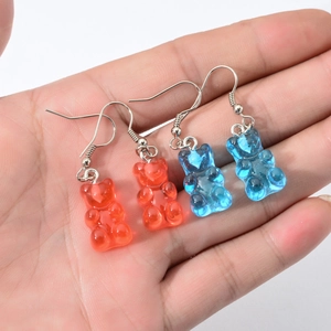 Schattige hars beer oorbellen in oranje en blauw met zilveren haken op de hand