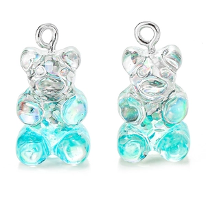 Macro shot of two transparent blue glitter resin bear pendants with silver hooks for DIY jewelry