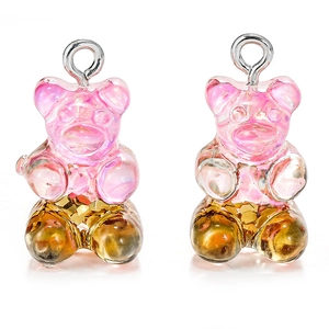 Close-up of pink glitter resin bear pendants with silver rings for DIY jewelry making