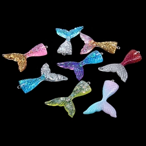 Close-up of sparkling colorful resin mermaid tail charms with glitter and silver rings