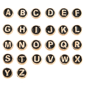 Vista macro di perline dorate con lettere A-Z in smalto nero per creazione gioielli fai da te