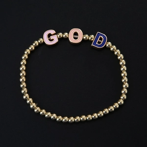 Dettaglio macro di perline dorate e ciondoli colorati con lettere GOD in smalto