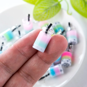 Macro shot of miniature milk tea charms held between fingertips for DIY jewelry size scaling