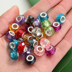 Macro shot of colorful faceted glass beads with silver metal cores held in palm for DIY