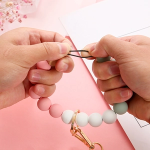 Pink and green silicone bead wristlet keychain with gold ring shown in a flexible stretch view
