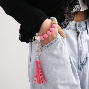 Silicone beaded wristlet keychain with wooden bead and pink leather tassel on hand