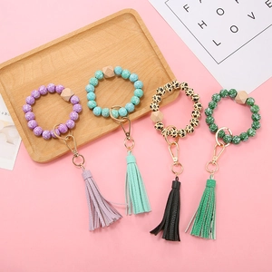 Detail of patterned silicone bead wristlets with leather tassels and gold metal clasps