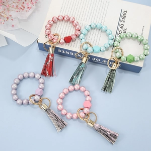 Five assorted silicone bead bracelet keychains with tassels and gold rings