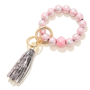Detail of pink floral wooden beads keychain bracelet with faux snakeskin tassel and golden ring