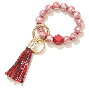 Detail of red silicone bead keychain with silver lace pattern and leather tassel pendant
