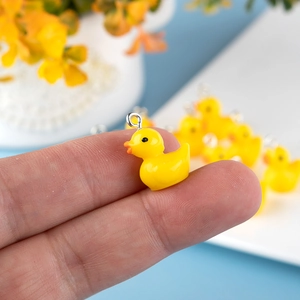 Detailed close-up of a cute yellow duck charm with a silver metal loop on a finger