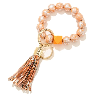 Detail of beaded keychain with orange wooden beads and snake pattern leather tassel
