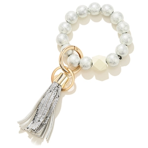 Detail of beaded keychain bracelet with floral wood beads and black snakeskin leather tassel