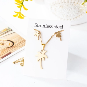 Macro detail of golden stainless steel palm tree pendant necklace and stud earrings set