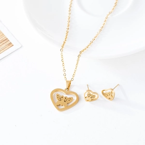Macro detail of golden heart necklace and earrings set with delicate butterfly pattern