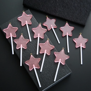 Macro-opname van tien roze sterlolly-hangers met glitter en gouden metalen ringetjes