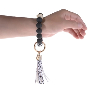 Beaded keychain bracelet featuring black matte beads with cow print charm and leather tassel