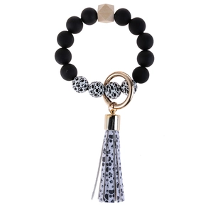 Close-up of cow print beads and wooden bead keychain bracelet with golden ring and tassel