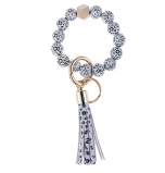 Detail of cow print beaded bracelet keychain with wooden bead and tassel accessory