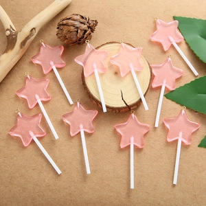 Detail van tien roze ster-lolly hangers van hars met glitter op houten achtergrond