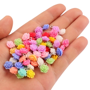 Ciondoli a forma di rosa in resina colorata per gioielli fai da te mostrati sulla mano
