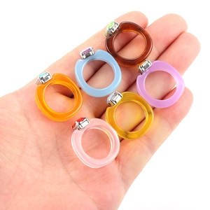 Detailed view of six colorful resin rings with inlaid rhinestones held in a hand