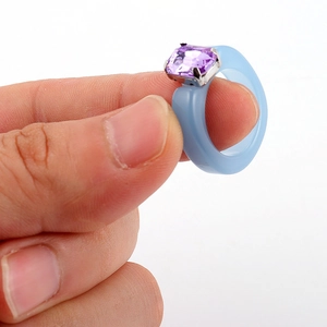 Macro detail of square purple crystal on a light blue resin ring with silver claw setting