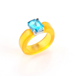 Detailed view of yellow resin ring with a rectangle blue crystal in silver claw setting