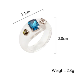 Anillo de resina transparente con un diamante de imitación azul y gemas laterales verdes