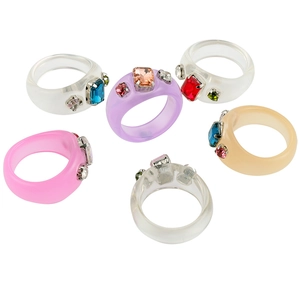 Detalle de anillos coloridos de resina acrílica con brillantes pedrería corte esmeralda