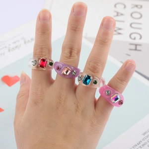 Primer plano de anillos de resina Y2K con cristales de colores sobre fondo de revista