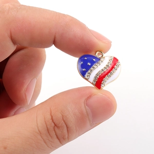 Macro view of heart-shaped American flag pendant with rhinestones held in fingers