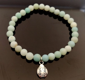 Vista detallada de la pulsera con cuentas mate turquesa y colgante de mariquita de plata