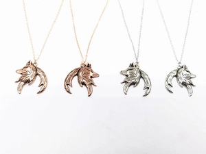Detail view of wolf head and moon necklaces in rose gold and silver finishes